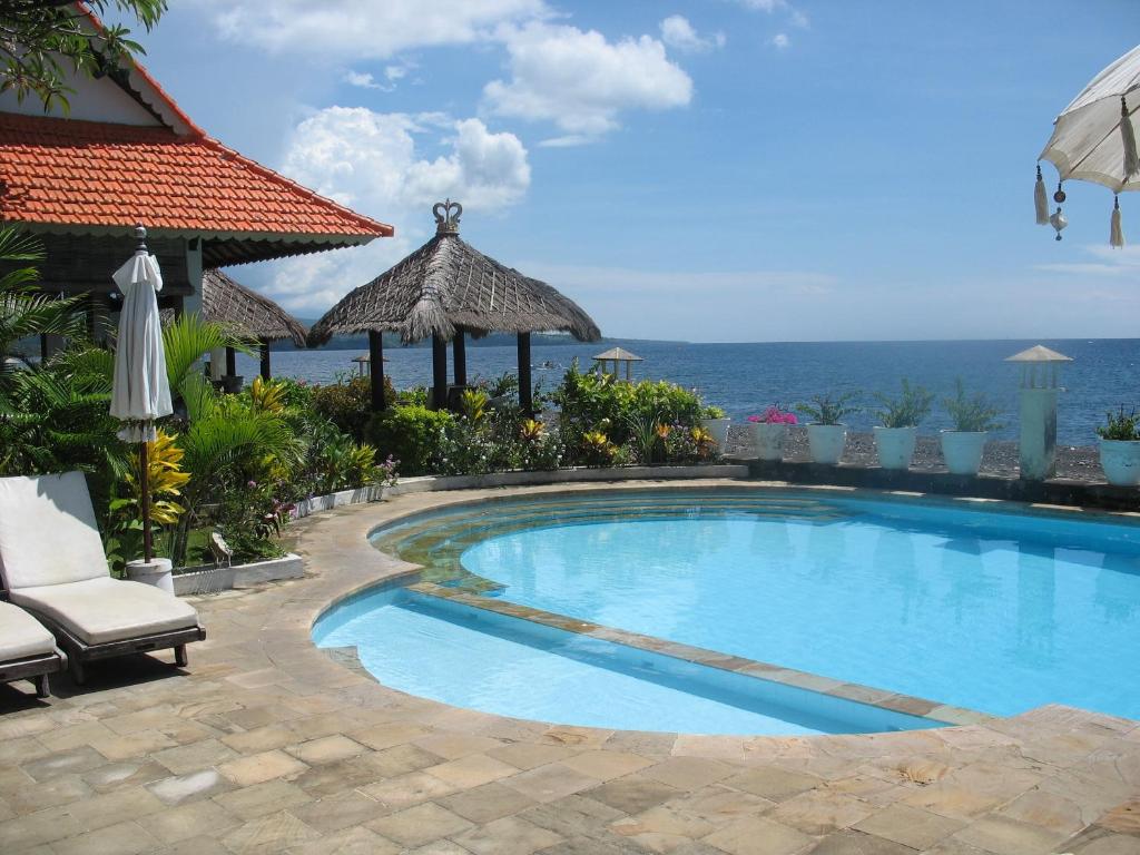 a swimming pool with a view of the ocean at Kembali Beach Bungalows in Amed