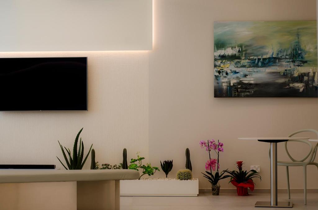 a living room with plants and a painting on the wall at Hermes Hotel in San Vito lo Capo