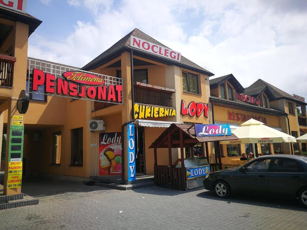 a car parked in front of a building with signs at Pensjonat Telimena in Zwierzyniec