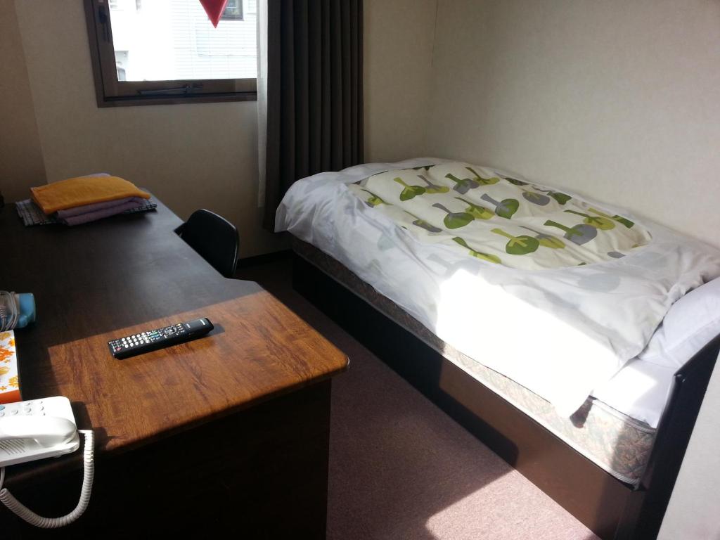 een slaapkamer met een bed en een bureau met een telefoon bij Hotel Wakasato in Nagano
