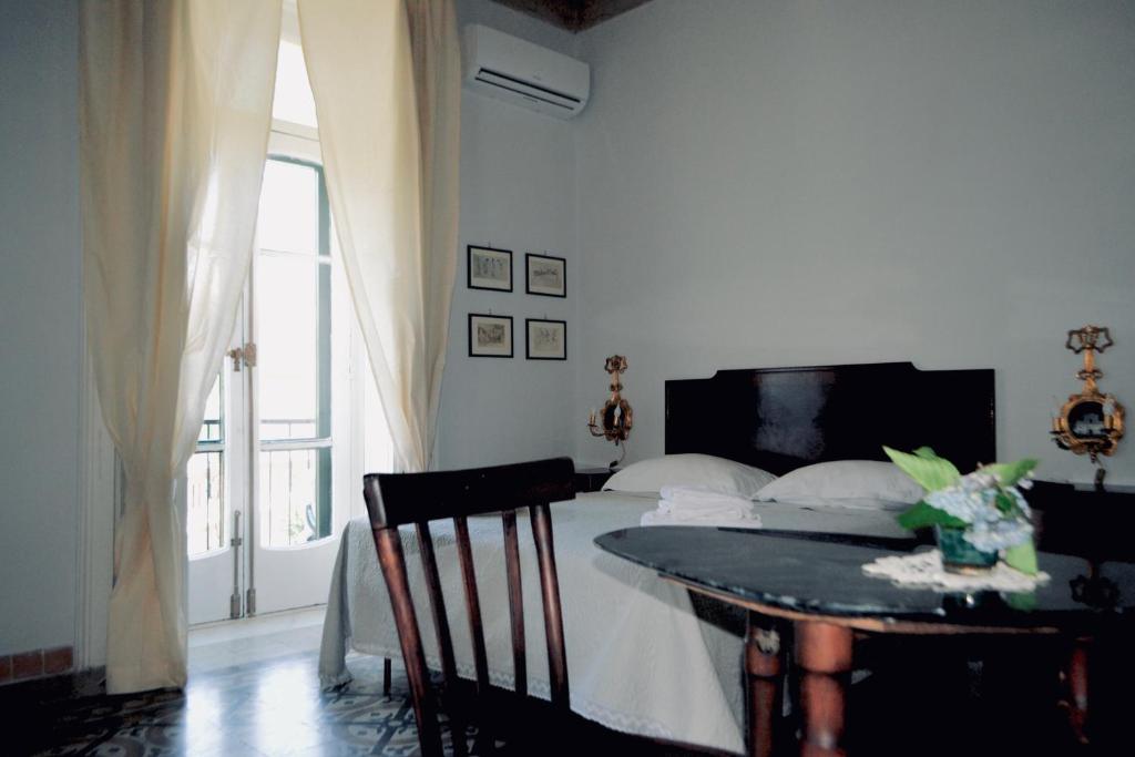 a bedroom with a bed and a table and a window at Borgo Civico 10 in Cava deʼ Tirreni