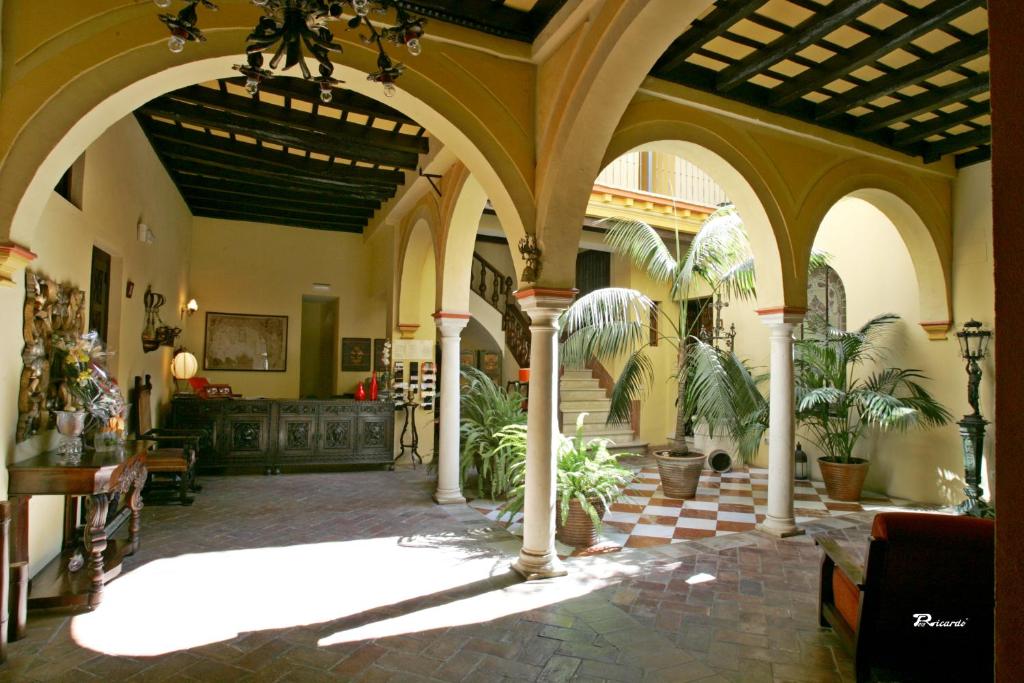 een grote kamer met zuilen en planten erin bij Posada de Palacio in Sanlúcar de Barrameda