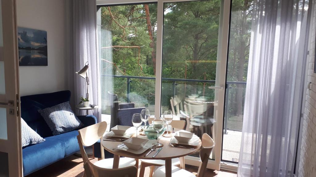 a living room with a table and chairs and a large window at Apartamenty nad Jeziorem Necko in Augustów