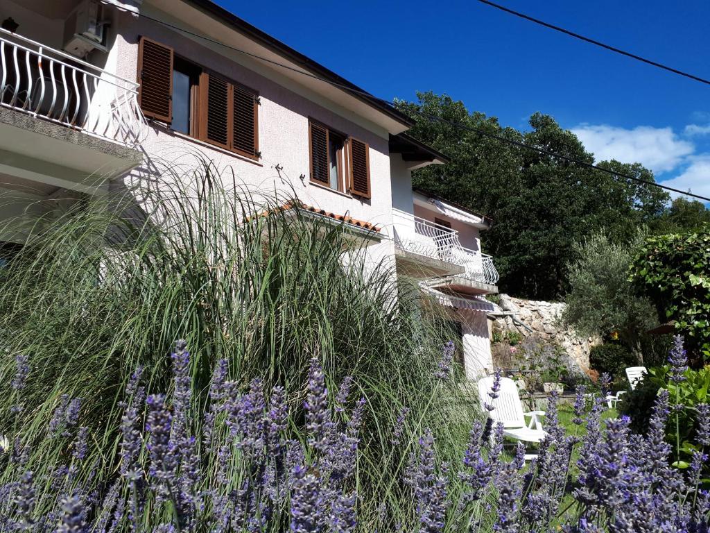 una casa con flores púrpuras delante de ella en Apartments & rooms MIKLEUS en Mošćenička Draga