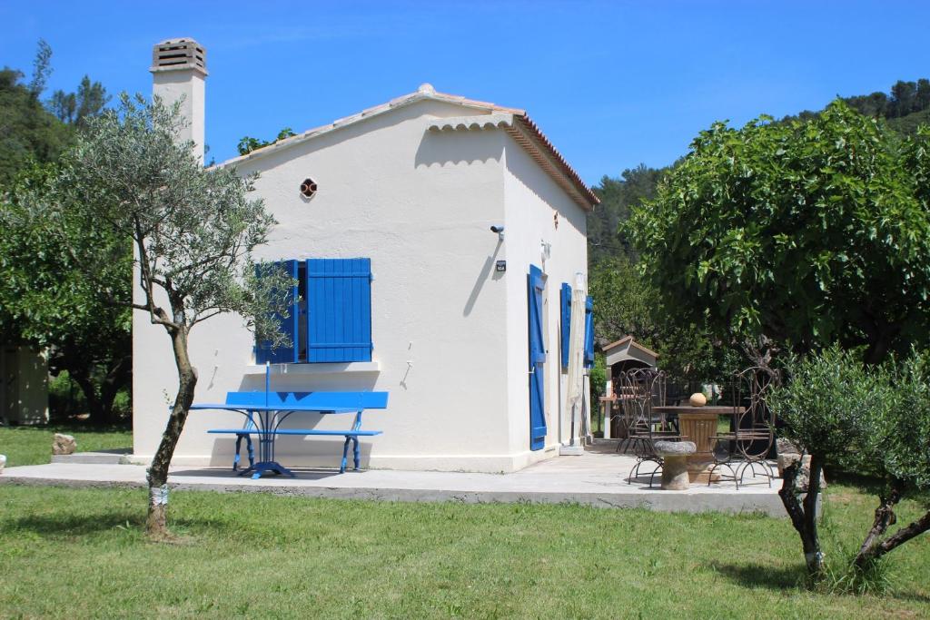 - un petit bâtiment blanc avec des portes bleues et une table de pique-nique dans l'établissement Cottage provençal, à Belgentier