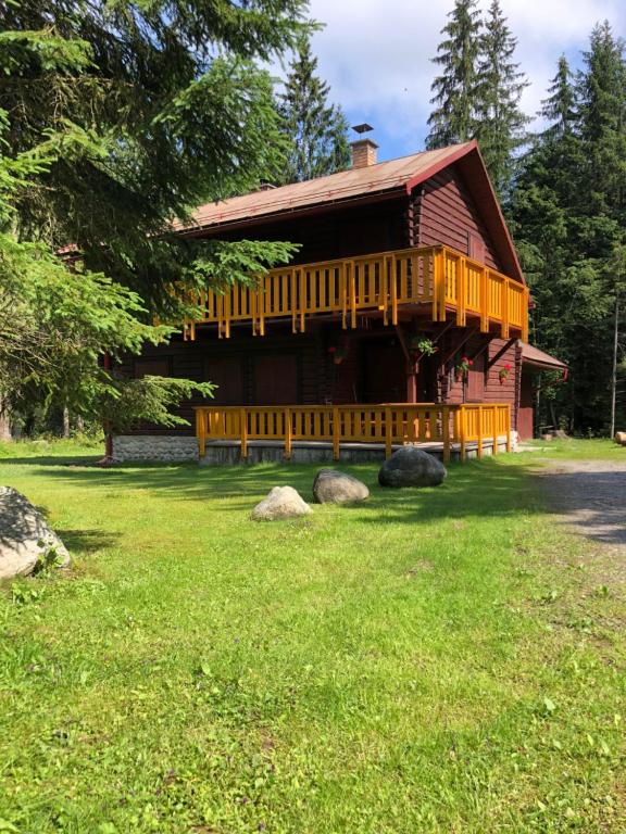 une grande cabane en bois avec une terrasse couverte sur une pelouse dans l'établissement Chata Pribisko 651, à Zuberec