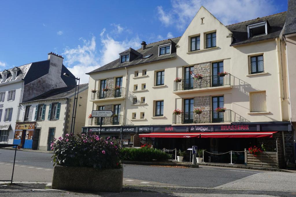 a large white building with flowers in front of it at Le Relais De La Place in Le Faou