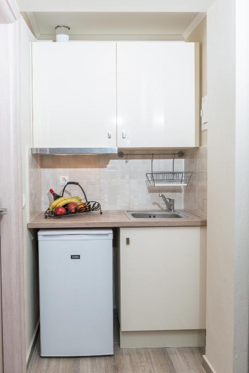 a kitchen with white cabinets and a sink at Ammos Beach Seaside Luxury Suites Hotel in Olympic Beach