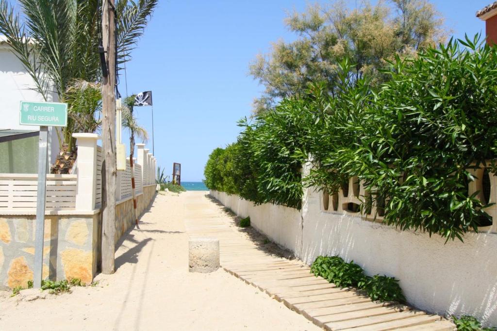 a sidewalk next to a wall with trees and the ocean at Santa Ana in Casas Devesa