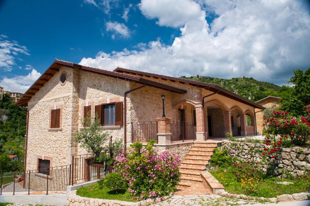 a stone house with a garden and flowers at Il Casale Della Regina in Arpino