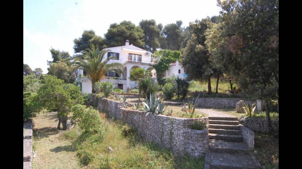 a large house with a stone wall and trees at Apartment in Maslinica 70m from the sea in Maslinica