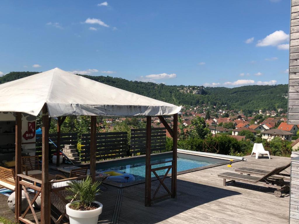 un patio con sombrilla y piscina en B&B Les Hauts d'Ornans en Ornans