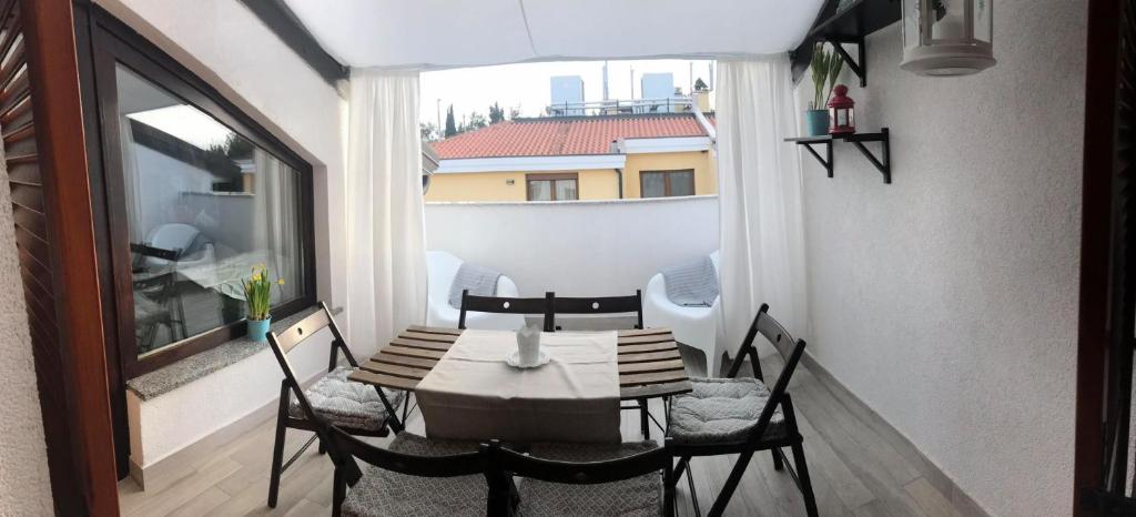 stół i krzesła na balkonie z oknem w obiekcie Apartments Michelle w mieście Umag