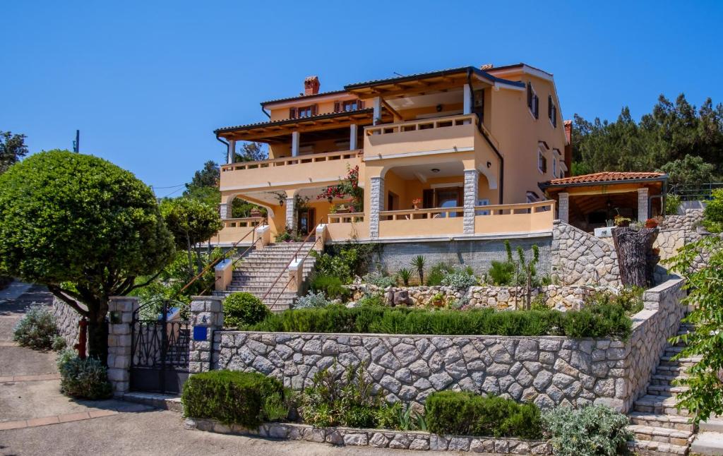 ein Haus auf einem Hügel mit einer Steinmauer in der Unterkunft Apartmani Zorica in Martinšćica