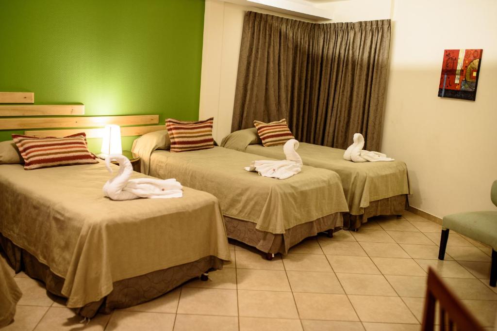 Dwa łabędzie siedzą na dwóch łóżkach w pokoju w obiekcie AVEMAR Apart Hotel w mieście Posadas