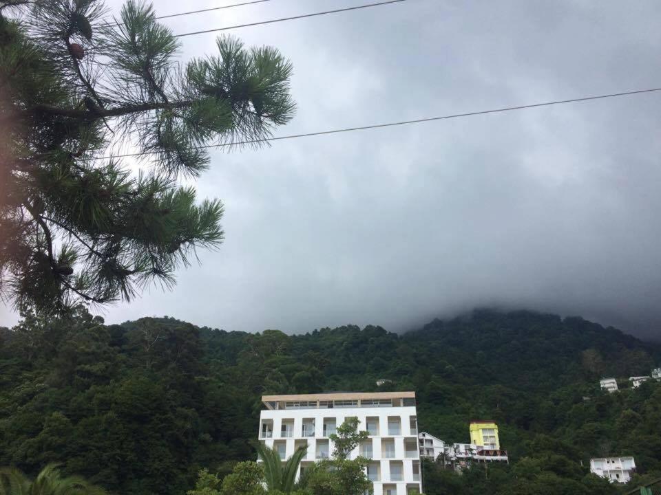 un edificio blanco frente a una montaña con nubes en Kvariati G, en Kvariati