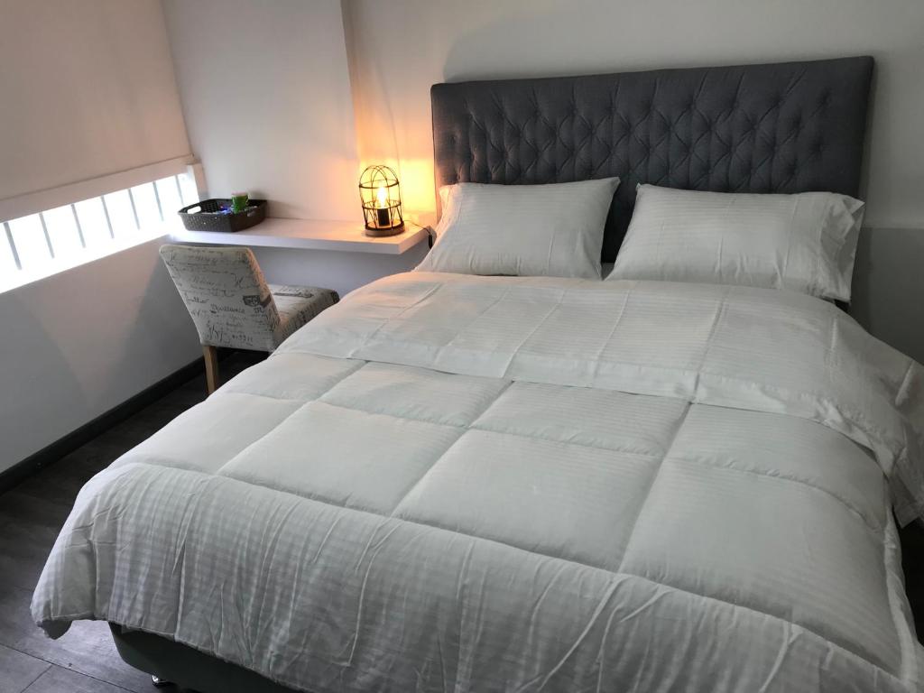 een slaapkamer met een groot wit bed en een stoel bij Hotel OrangeTrip in Bogota