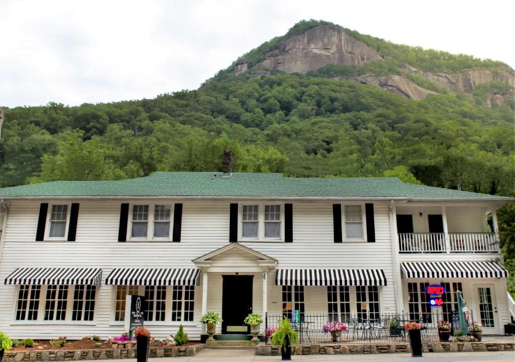a white house with a mountain in the background at Broad River Inn in Chimney Rock