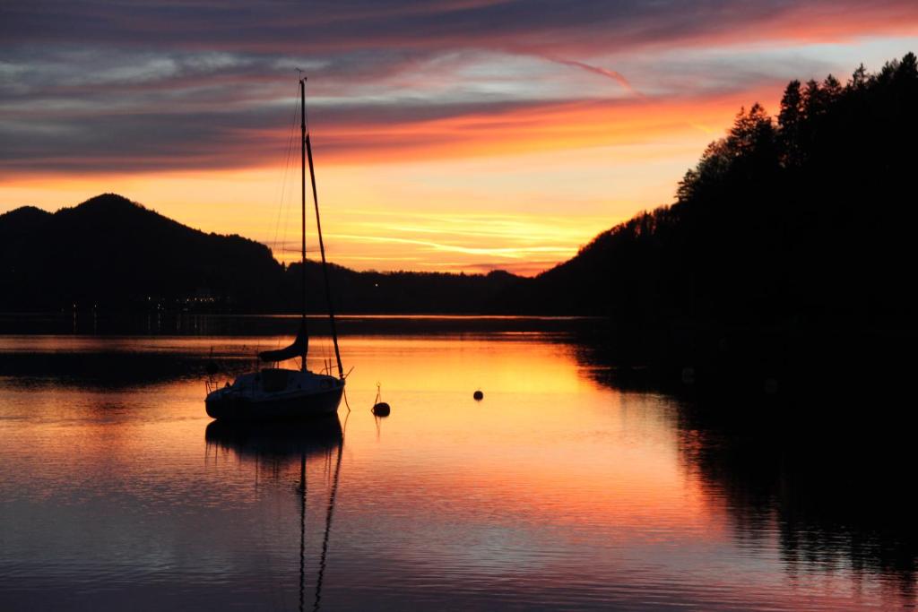 a sail boat sitting in the water at sunset at Hotel Seewinkel in Fuschl am See