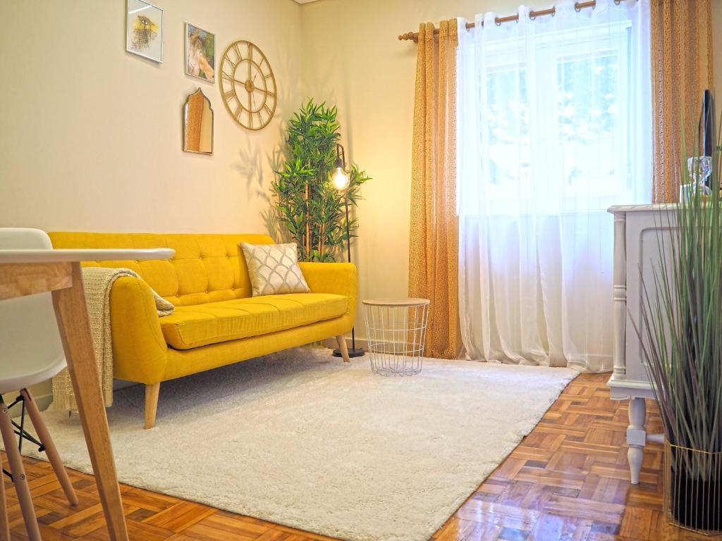 a living room with a yellow couch and a window at Viana Lovers in Viana do Castelo