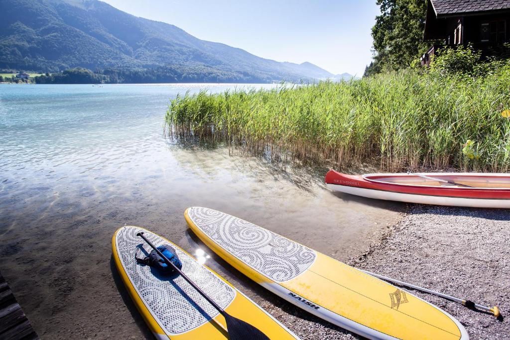 three kayaks on the shore of a body of water at Hotel Seewinkel in Fuschl am See