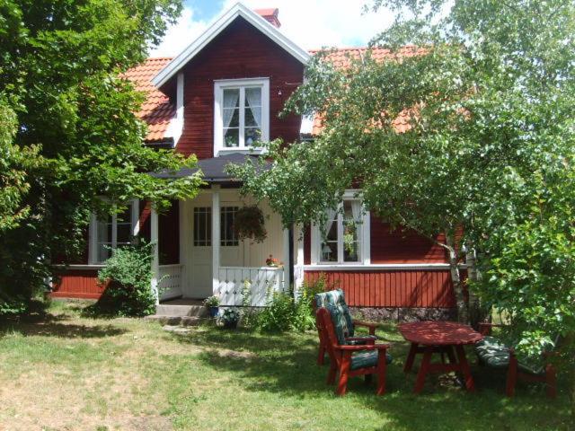 a red house with a table and chairs in the yard at Karlstugan Cottage in Vimmerby