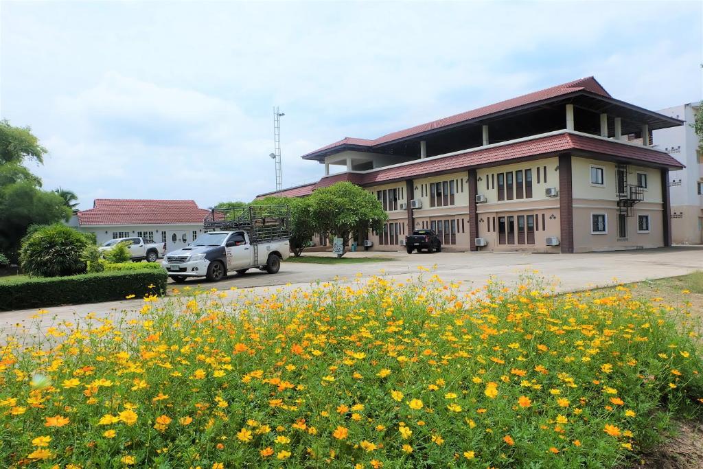 ein Gebäude mit vielen gelben Blumen davor in der Unterkunft Royal Princess City Lamphun Hotel in Lamphun