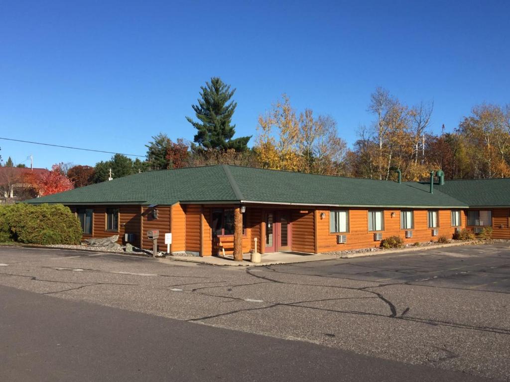 a large wooden building with a green roof at Northwoods Inn & Suites Minocqua in Minocqua