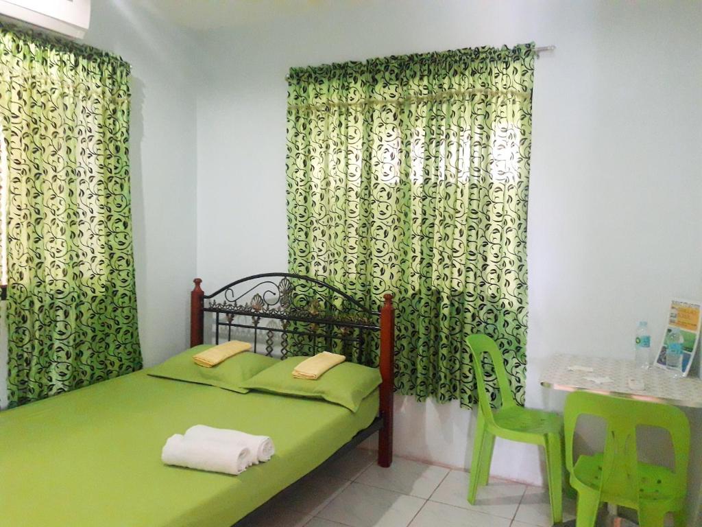 um quarto com uma cama verde e 2 cadeiras verdes em D downhill'Place em Oslob
