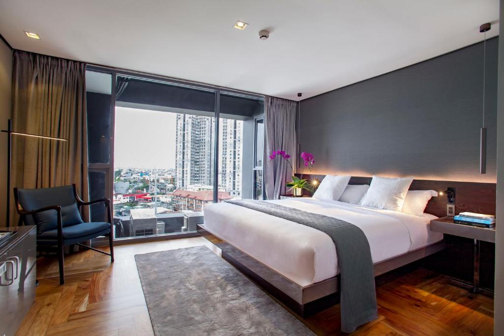 a bedroom with a large bed and a large window at Ramada Encore by Wyndham Makati in Manila