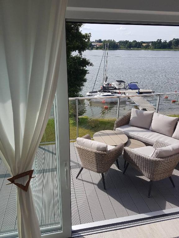 patio ze stołem, krzesłami i łodzią w obiekcie Apartament z widokiem na jezioro w Rydzewie