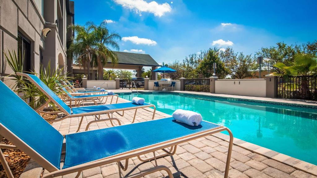 uma piscina com espreguiçadeiras azuis ao lado de um edifício em Best Western Airport Inn Fort Myers em Fort Myers