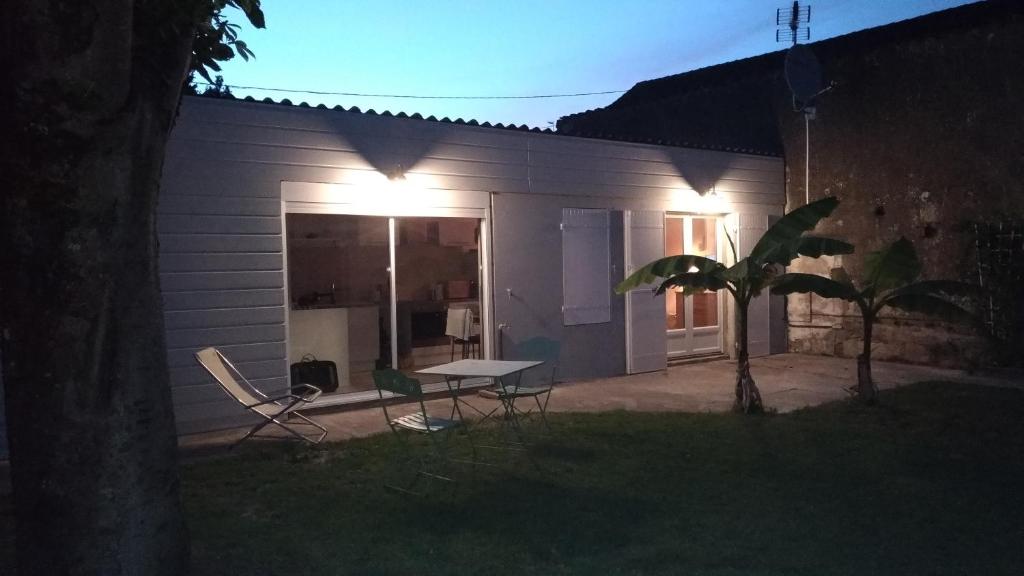 a house with a table and chairs in the yard at Le Bananier in Saint-Fort-sur-Gironde