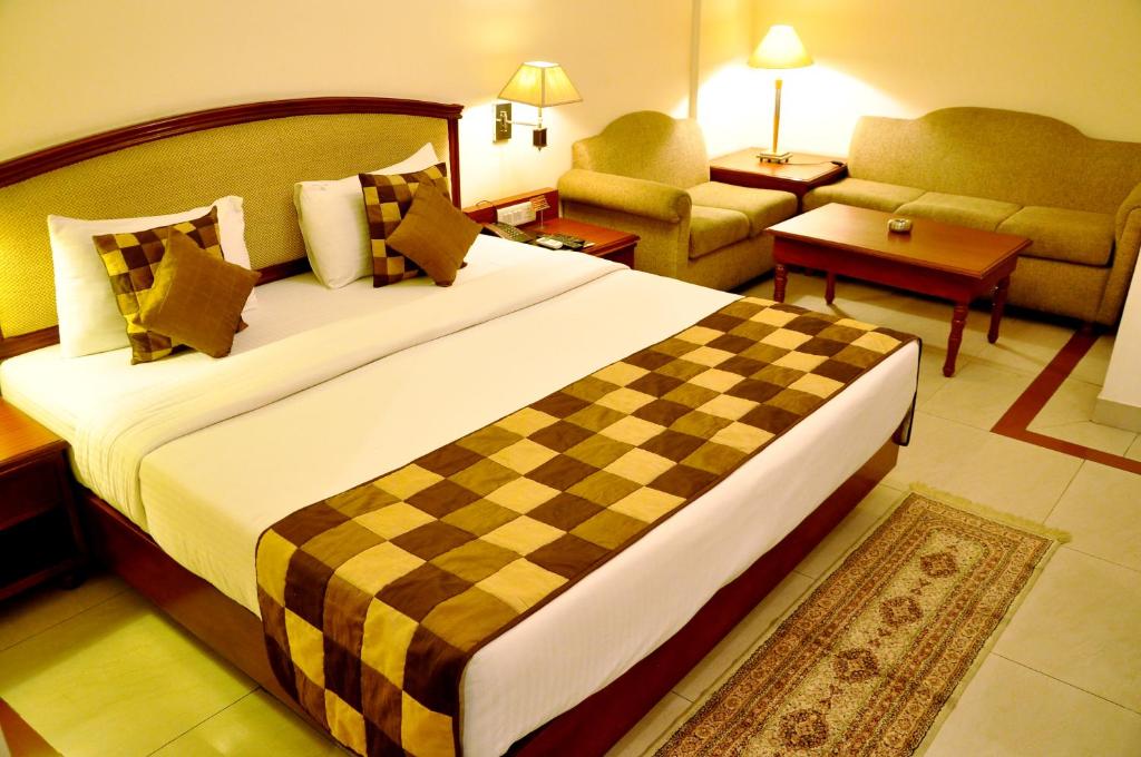 a hotel room with a large bed and a living room at Hotel Jewel Palace in New Delhi