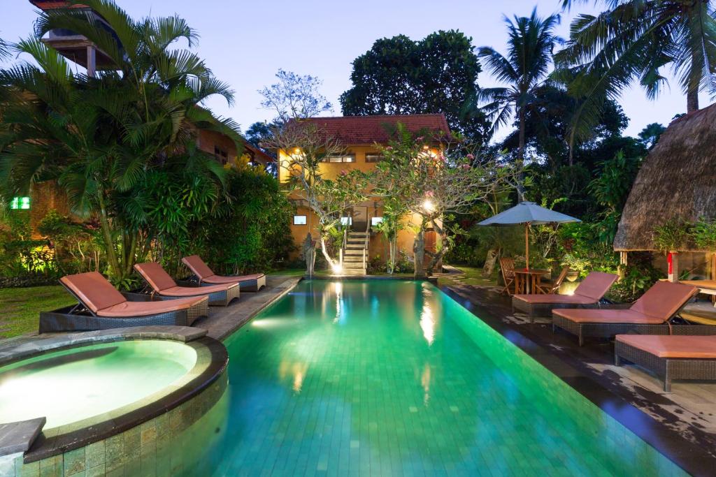 a swimming pool with lounge chairs and a resort at Wenara Bali Bungalows in Ubud