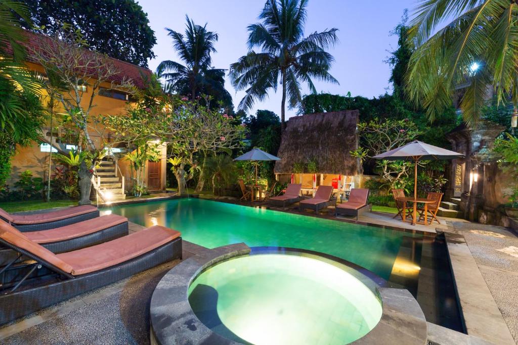 a swimming pool with lounge chairs and a resort at Wenara Bali Bungalows in Ubud