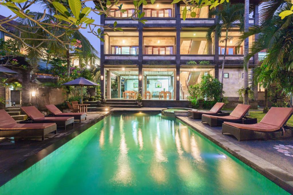 une piscine avec des chaises longues et une maison dans l'établissement Wenara Bali Bungalows, à Ubud