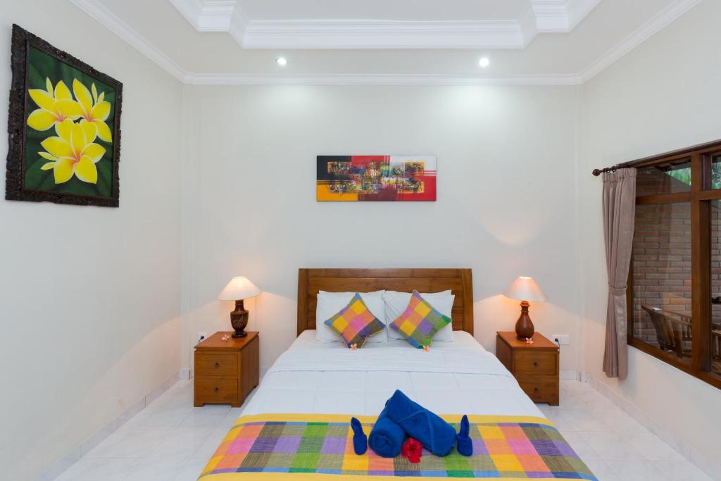 a bedroom with a bed with blue shoes on it at Wenara Bali Bungalows in Ubud