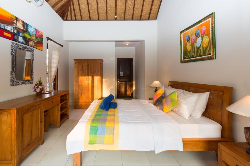 a bedroom with a large white bed and a desk at Wenara Bali Bungalows in Ubud