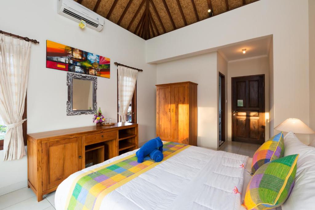 a bedroom with a large bed with a blue stuffed animal on it at Wenara Bali Bungalows in Ubud