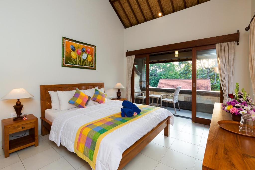 a bedroom with a large bed and a balcony at Wenara Bali Bungalows in Ubud