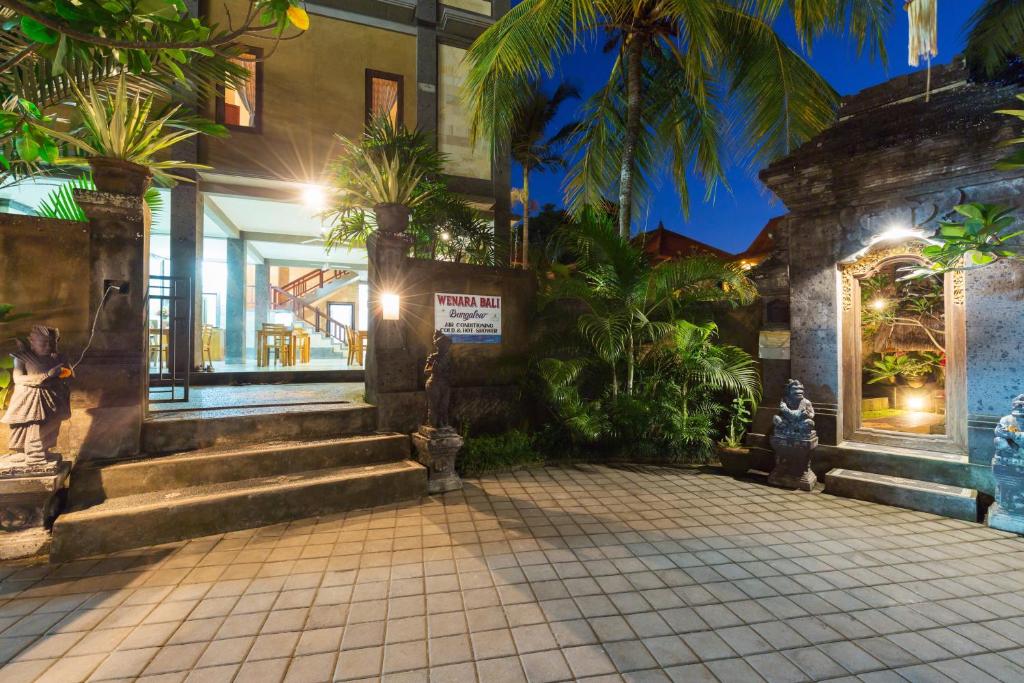 a building with stairs and palm trees in front of it at Wenara Bali Bungalows in Ubud