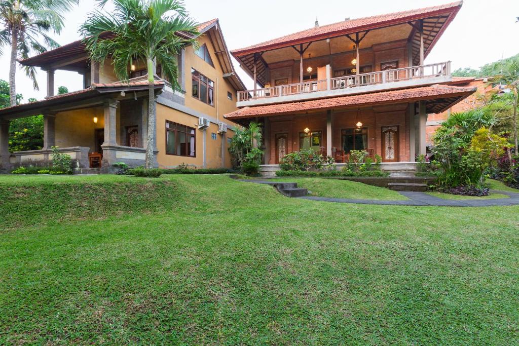 a large house with a lawn in front of it at Wenara Bali Bungalows in Ubud
