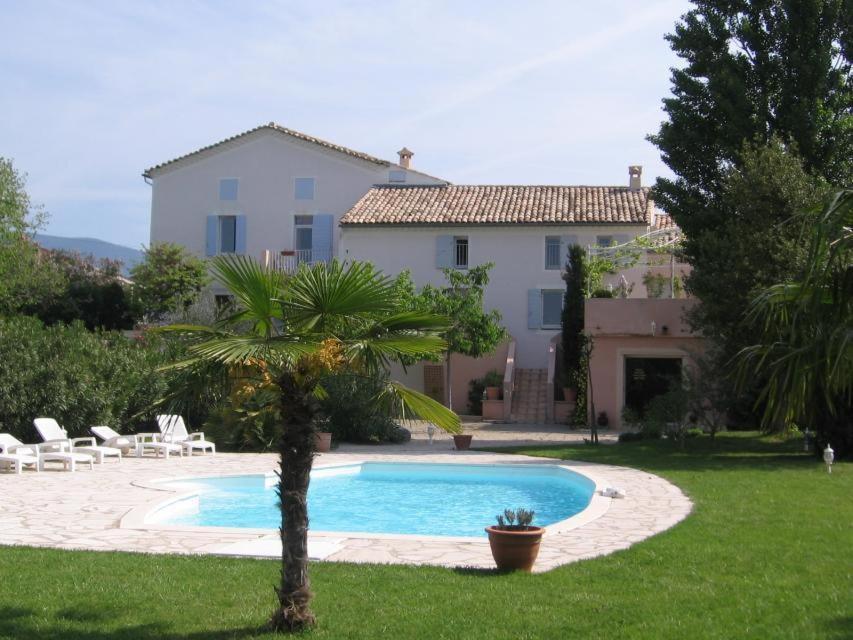une villa avec une piscine en face d'une maison dans l'établissement Hôtel La Bastide des Monges, à Nyons