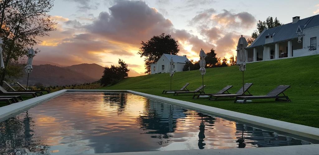 a pool in front of a house with a sunset at La Cotte Forest Cottages in Franschhoek