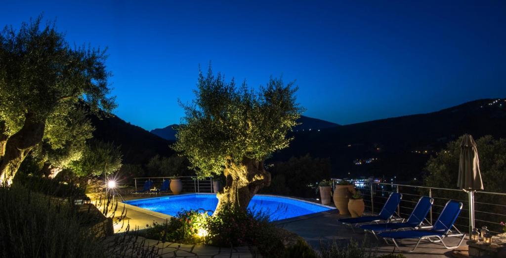 a swimming pool with chairs and a tree at night at Villas Amantea- four villas with big pool and infinity pool in Sivota