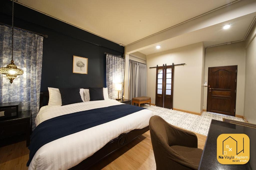 a bedroom with a large bed and a chair at Na Vayla PaPlern in Bangkok