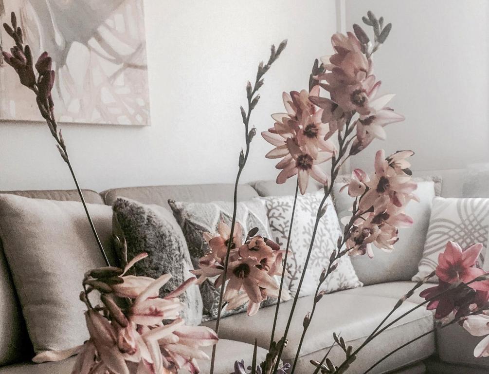 a vase with pink flowers on a couch at Bed of Roses in Apollo Bay