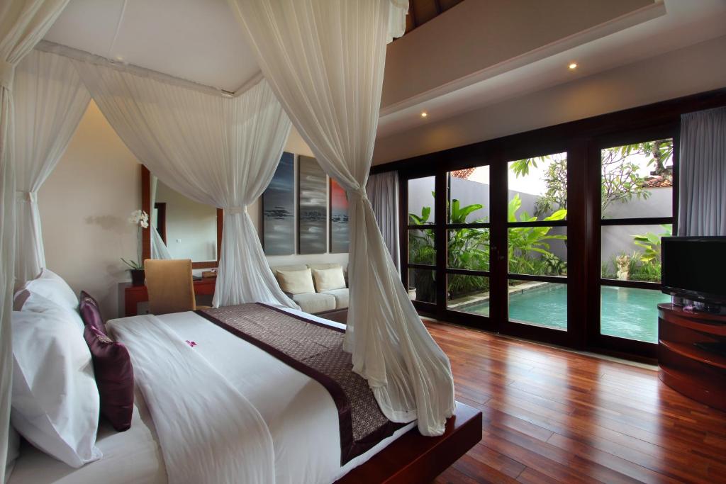 a bedroom with a bed with white drapes at Aria Exclusive Villas & Spa - CHSE Certified in Seminyak