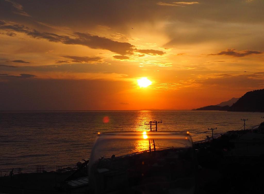 una puesta de sol sobre el océano con un barco en el agua en Filanthi Apartments, en Paralia Vrachou